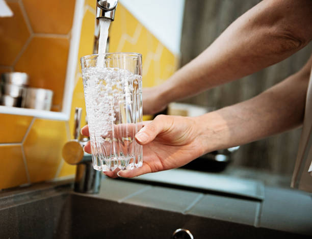 Woman fills glass with water directly from sink tap to represent Precise Plumbing and Heating services for plumber Midvale UT